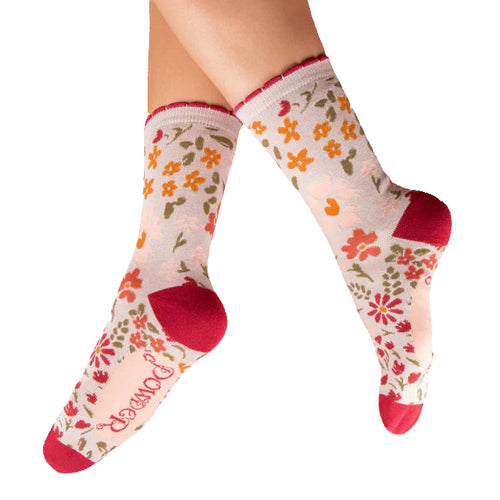 Floral patterned socks with red accents worn by a person on a white background