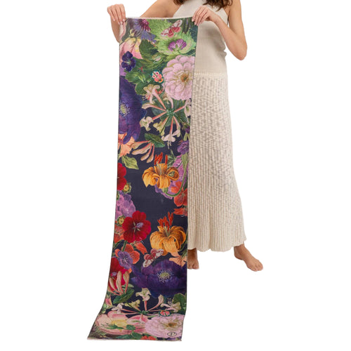 Person holding a colorful floral scarf with a dark purple background on a white background