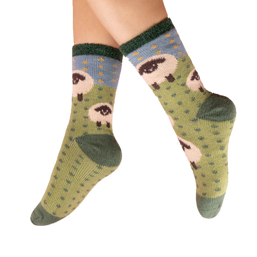 Green socks with sheep pattern worn by a person on a white background