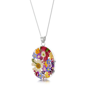 Necklace with a silver chain and an oval pendant of mixed colouful flowers encased in resin.